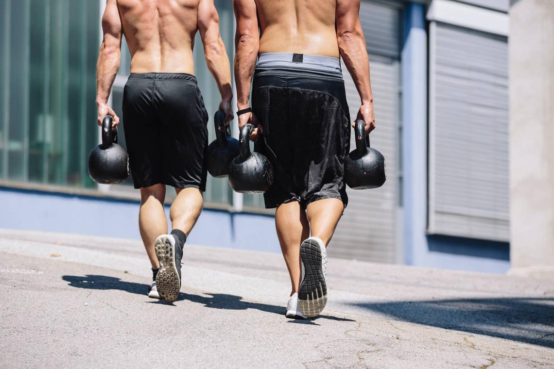  zwei CrossFit Athleten beim Farmers Walk mit Kettlebells. 
