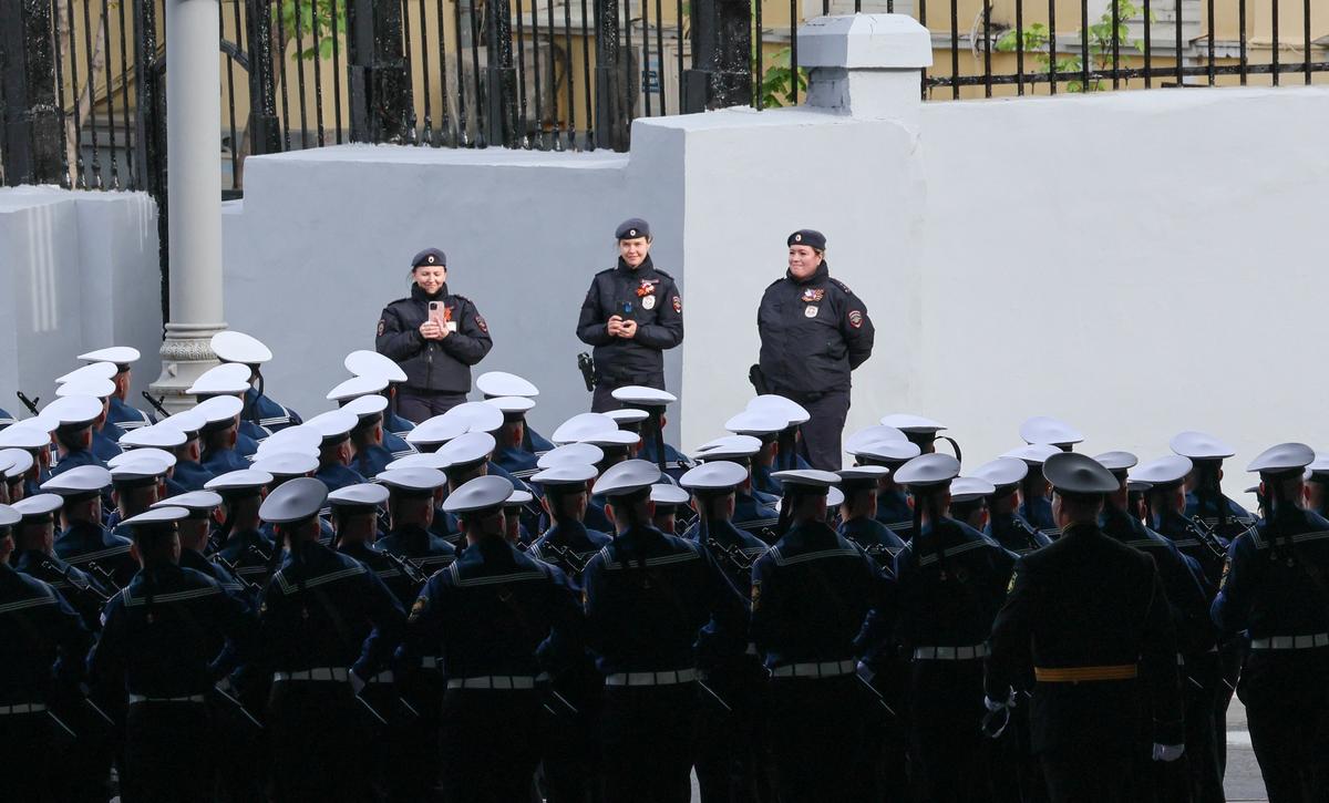 Police officers take pictures of Russian service members lining up before a military parade on Victory Day, marking the 81st anniversary of the victory over Nazi Germany in World War Two, in central Moscow, Russia, May 9, 2026. REUTERS/Anastasia Barashkova