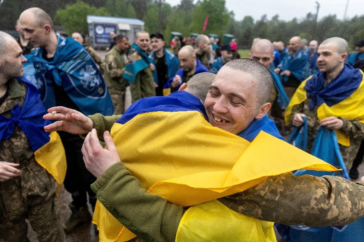 Ukrainian servicemen and former prisoners of war (POW) embrace after they set foot on Ukrainian soil after a POW swap with Russia, amid Russia's attack on Ukraine, at an undisclosed location in Ukraine May 15, 2026. REUTERS/Thomas Peter
