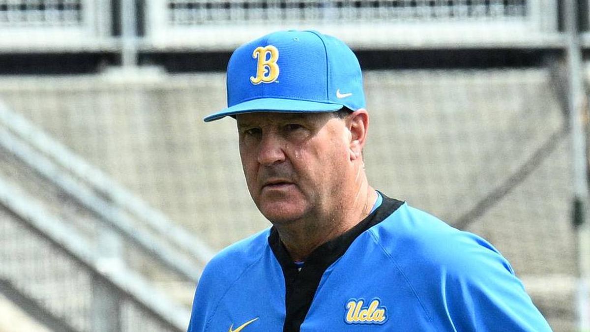  Jun 17, 2025; Omaha, Neb, USA; UCLA Bruins head coach John Savage (22) walks to the dugout before the restart of the game against the LSU Tigers at Charles Schwab Field. Mandatory Credit: Steven Branscombe-Imagn Images | Steven Branscombe-Imagn Images 