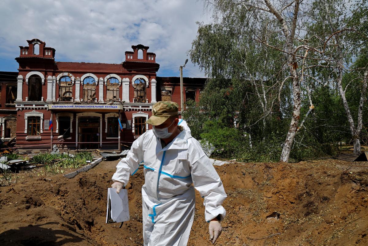 An investigator inspects a crater in front of the destroyed building of the Starobilsk College of Luhansk Pedagogical University following a recent attack, which Russian authorities called a Ukrainian drone strike, in the course of the Russia-Ukraine conflict in the town of Starobilsk (Starobelsk) in the Luhansk region, a Russian-controlled area of Ukraine, May 24, 2026. Reuters reported from Starobilsk on a media facility trip organised by the Ministry of Foreign Affairs of the Russian Federation on May 24, 2026. REUTERS/Alexander Ermochenko
