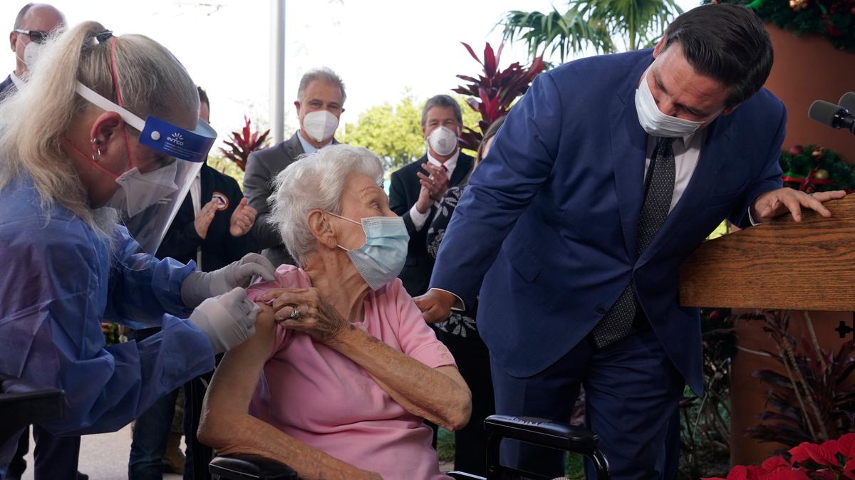 En esta foto de archivo del 16 de diciembre de 2020 el gobernador Ron DeSantis le pregunta a Vera Leip, de 88 años, cómo se siente después que la enfermera Christine Philips, a la izquierda, la vacunó en  Pompano Beach, Florida.