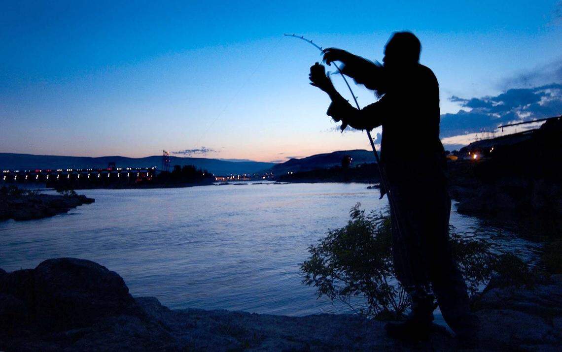 An angler places a weight on the fishing pole while angling for Columbia River salmon and steelhead across from The Dalles Dam.