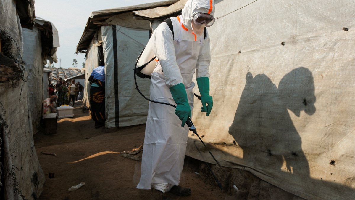 A health worker in full personal protective equipment (PPE) disinfects an area while preparing for the burial of suspected Ebola victims at the Kigonze displaced persons camp in Bunia, eastern Democratic Republic of Congo, on June 18, 2026, one month after the outbreak was declared. REUTERS/Gradel Muyisa Mumbere