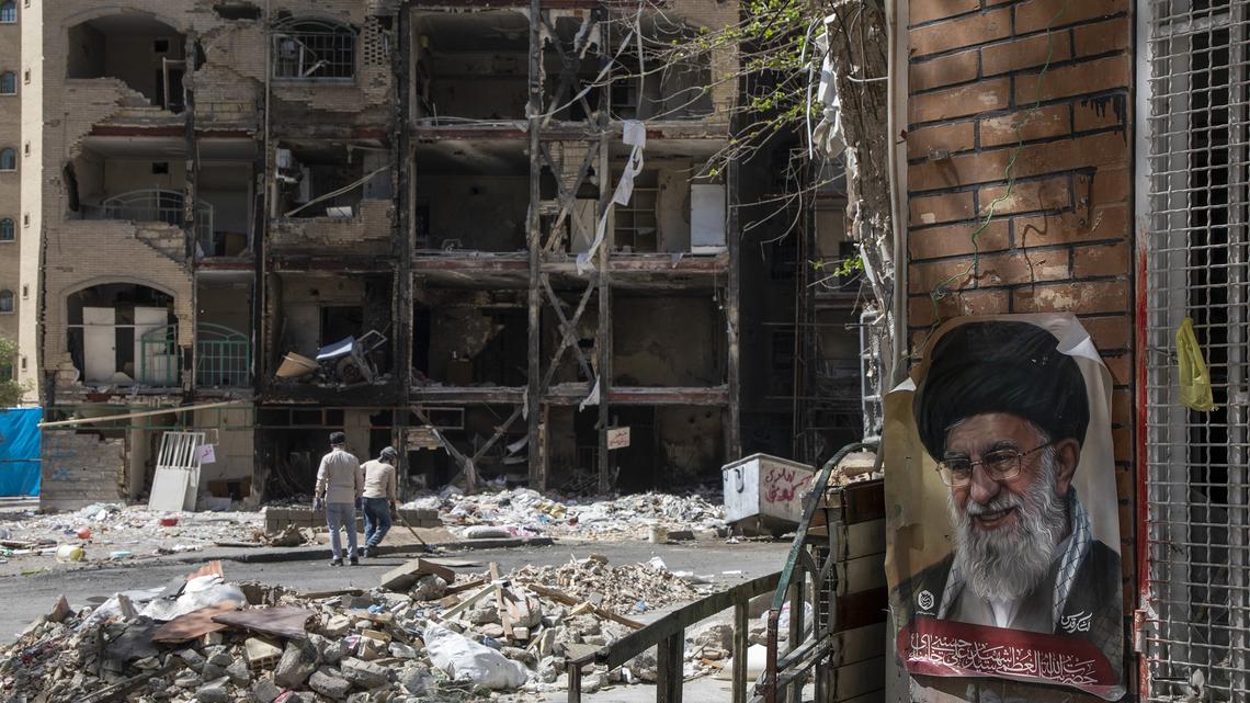 Men walk past a damaged residential building that, according to Iranian authorities, was hit by a strike on March 4 during the U.S.-Israeli military campaign on April 14, 2026, in southeastern Tehran, Iran. On April 8 President Donald Trump announced a two-week ceasefire between the US and Iran, conditional on shipping being allowed to resume through the Strait of Hormuz. Peace talks held in Pakistan have since stalled, reportedly over Iran's nuclear stockpile and continued blockade of the Strait of Hormuz. (Majid Saeedi/Getty Images/TNS)