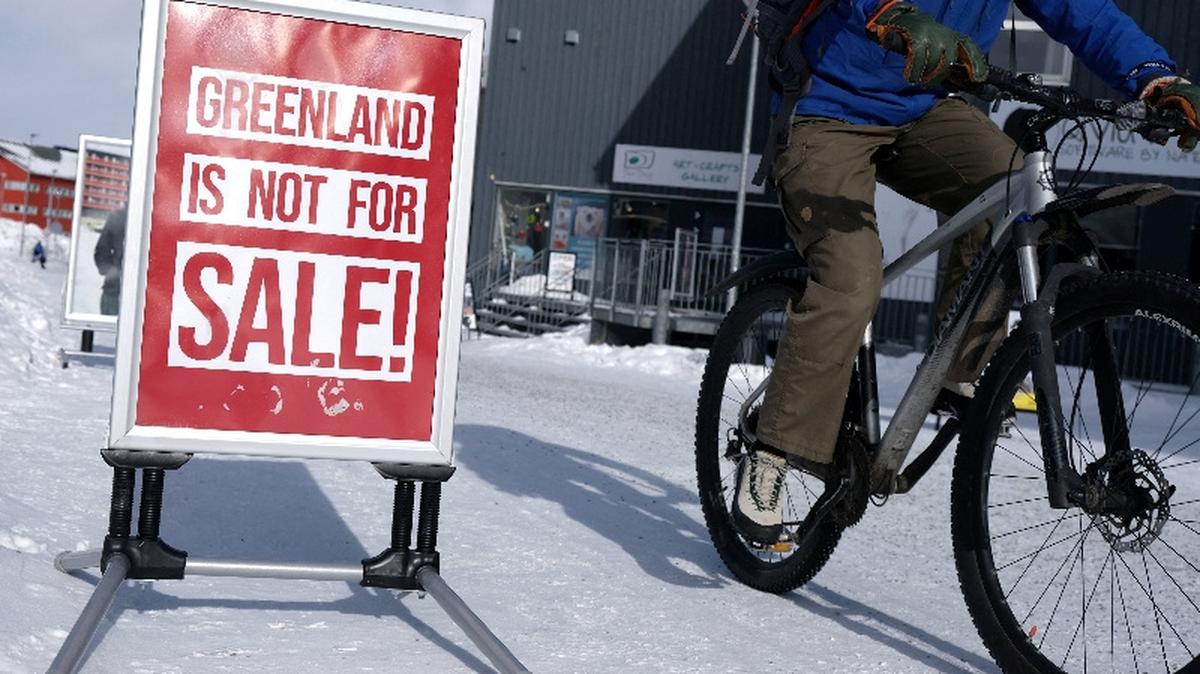 A person cycles past a poster in Nuuk, Greenland, March 17, 2026. REUTERS/Tim Barsoe