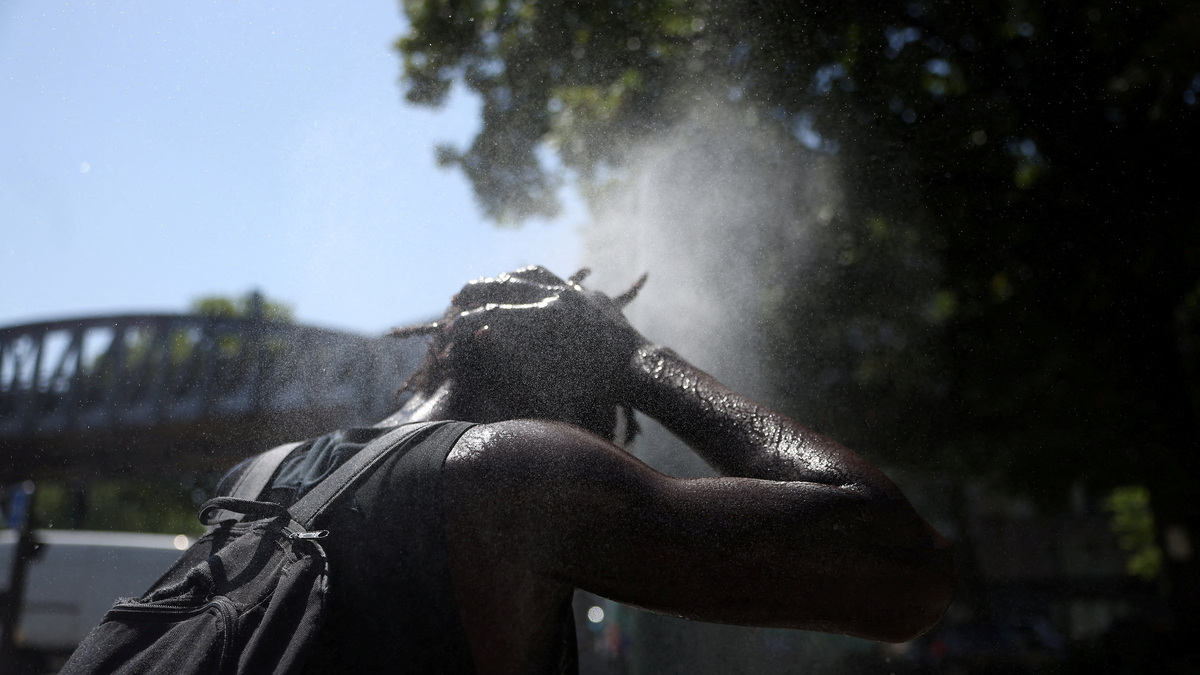 A person cools off at a water mister on a street in Paris as temperatures rise during a heatwave affecting a large part of France, June 22, 2026. REUTERS/Alice Sacco