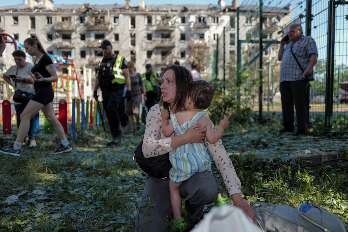 A woman holds a child, near an apartment building damaged during a Russian missile and drone strike, amid Russia's attack on Ukraine, in Kyiv, Ukraine July 2, 2026. REUTERS/Viacheslav Ratynskyi