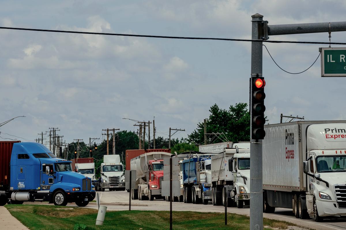 Trucks line up at a busy intersection after departing from several distribution centers, including an Amazon cross-dock facility, in Joliet, Ill. on June 30, 2025. 25 years ago, the far outskirts of the Chicago suburbs were mostly farmland. Today, warehouse complexes dominate. With them, the roads have become increasingly dangerous. (Jamie Kelter Davis/The New York Times)....