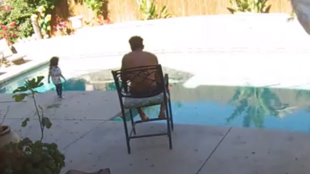 A still image from a home security camera shows Keoki Silva in his backyard as his toddler daughter, Aria, approaches the pool. 