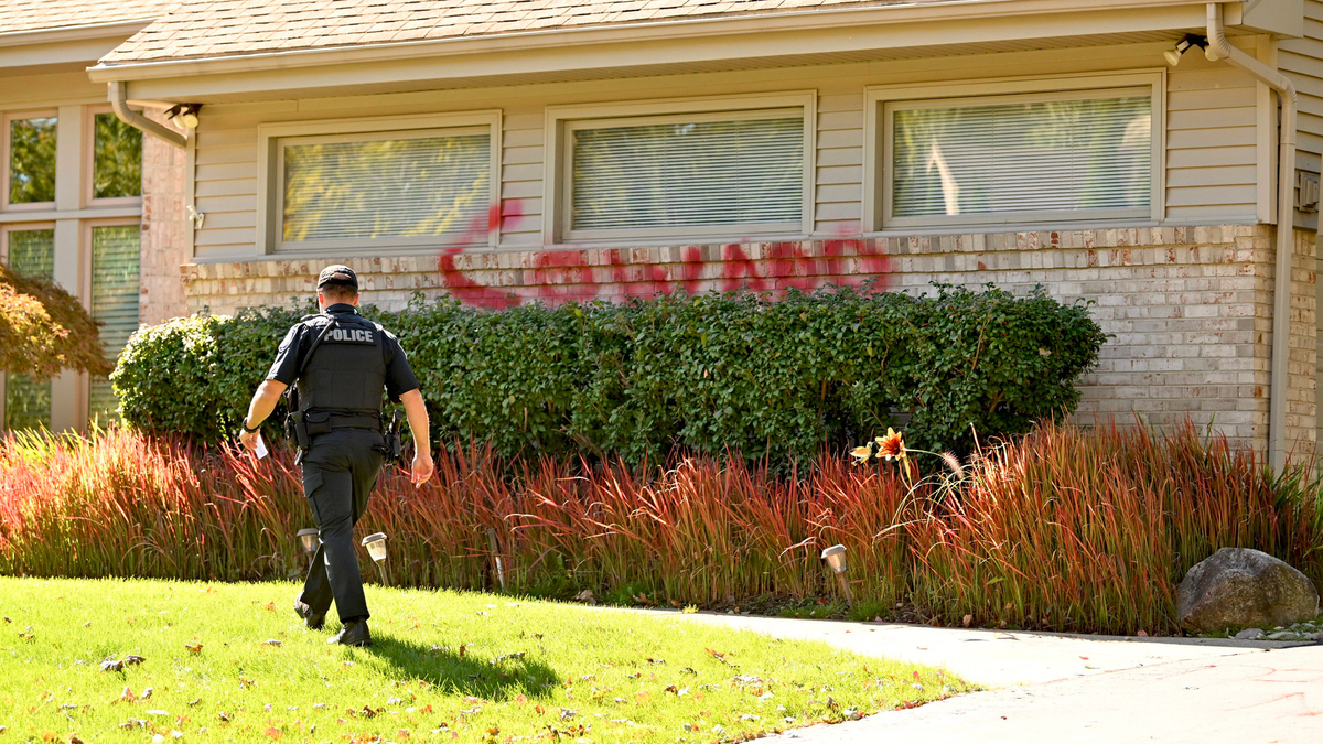 A West Bloomfield police officer walks across the lawn at the home of University of Michigan President Santa Ono, whose house defaced with graffiti, including the word coward on a brick exterior wall on Monday, Oct. 7, 2024. Today is the one year anniversary of the Oct. 7, 2023 Hamas-led attack on Israel. (David Guralnick/The Detroit News/TNS)