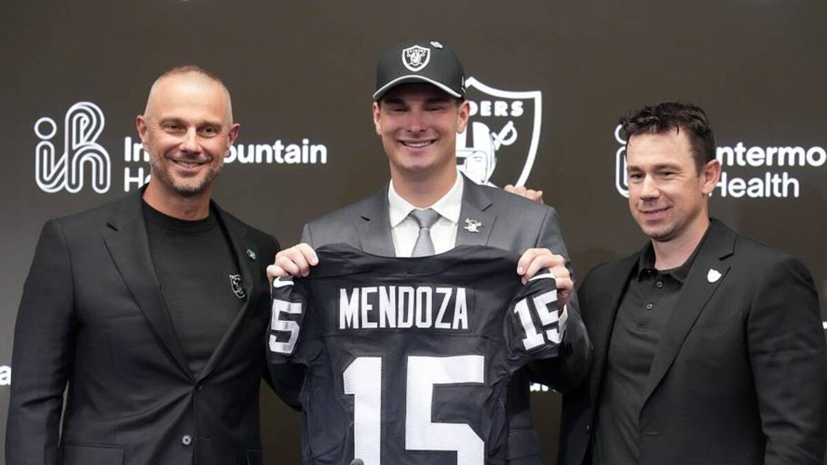  Apr 24, 2026; Henderson, NV, USA; Las Vegas Raiders quarterback Fernando Mendoza (center) poses with jersey at introductory press conference at Intermountain Health Performance Center flanked by general manager John Spytek (left) and head coach Klint Kubiak after being selected as the No. 1 pick in the 2026 NFL Draft. Mandatory Credit: Kirby Lee-Imagn Images | Kirby Lee-Imagn Images 