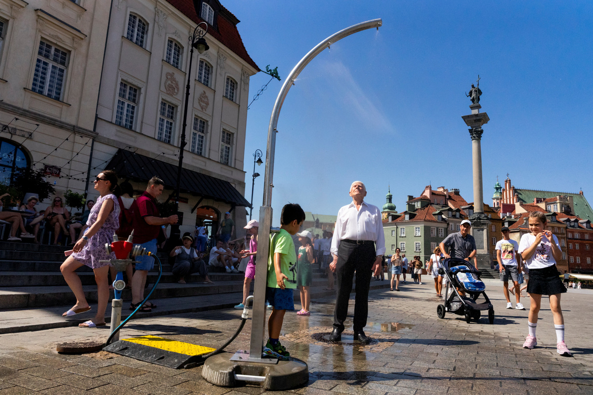 People gather at a mist dispenser to cool off during a heatwave, at Castle Square in Warsaw, Poland, June 27, 2026. REUTERS/Mateusz Kaczmarek