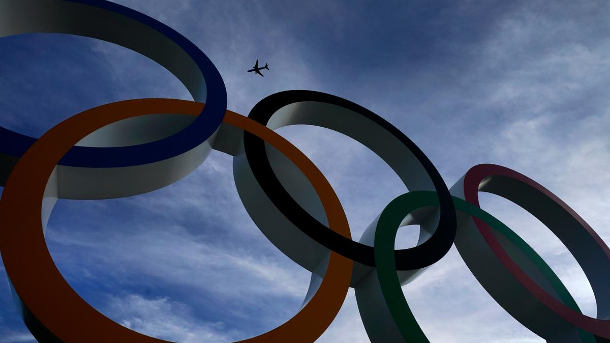 A passenger jet flies over the Olympic rings on display outside the Olympic Stadium where the athletic events are underway at the 2020 Summer Olympics Thursday, Aug. 5, 2021, in Tokyo, Japan. (AP Photo/Charlie Riedel)