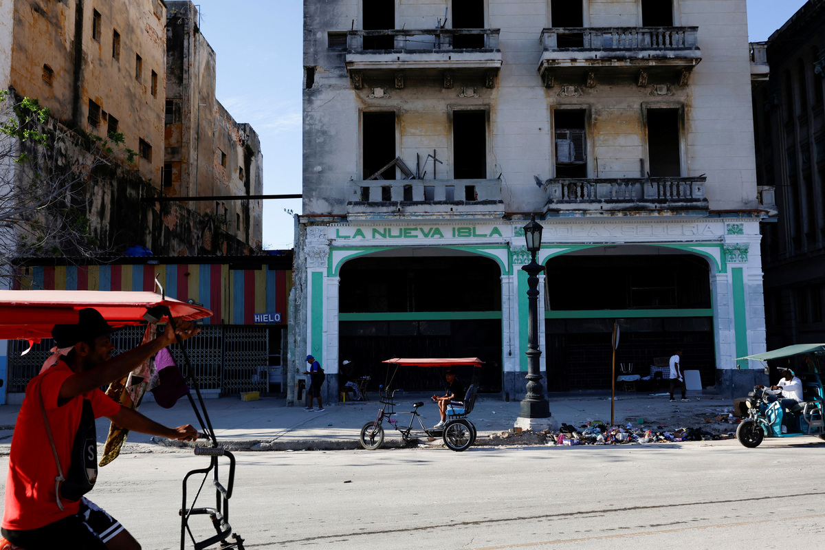 A bicitaxi driver rides past a building with the name "The New Island” on its facade, before the Cuban government presents far-reaching economic measures that could mark the most significant shift toward a market economy since the 1959 revolution, in Havana, Cuba June 17, 2026. REUTERS/Norlys Perez
