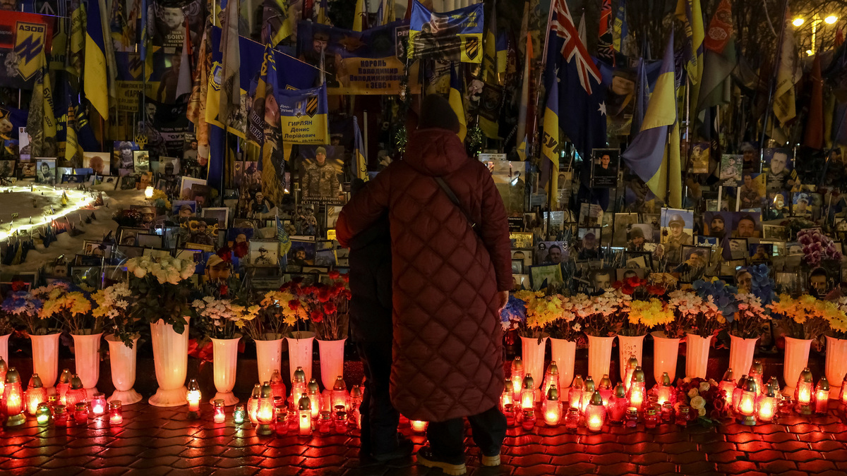People stand near lit candles at a makeshift memorial for fallen Ukrainian defenders to mark the fourth anniversary of the full-scale Russian invasion, amid Russia's attack on Ukraine, at the Independence Square in Kyiv, Ukraine, February 24, 2026. REUTERS/Stringer