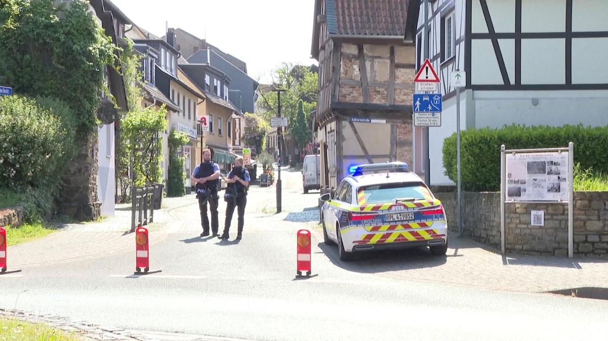 Police officers stand guard next to a police vehicle, during operations in response to a hostage-taking situation, at a savings bank branch in the western town of Sinzig, near Bonn, in the state of Rhineland-Palatinate, Germany, in this screengrab obtained from video, May 8, 2026. REUTERS TV via REUTERS
