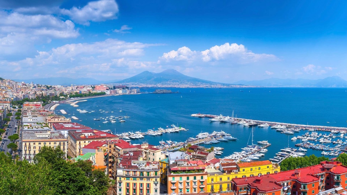 A aerial view of the coastline in Naples, Campania, Italy with Mount Vesuvius in the distance.