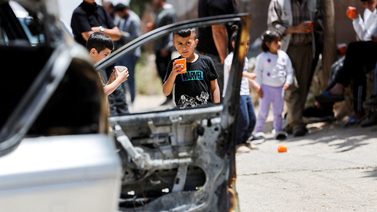 FILE PHOTO: Children stand near a damaged car, which Palestinians say was burned by Israeli settlers,in Halhul near Hebron in the Israeli-occupied West Bank May 20,2026. REUTERS/Mussa Qawasma/File Photo