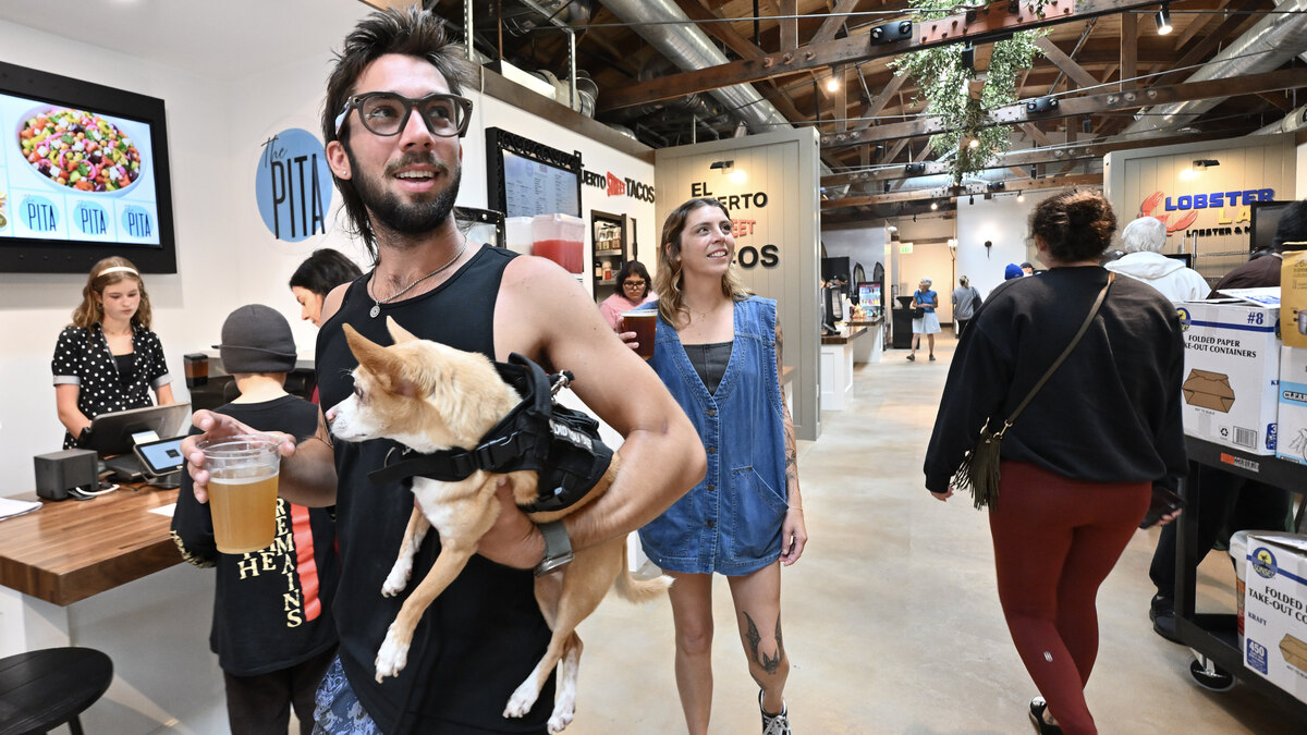 Aaron Werdmuller holds his dog Wilbur as he joins his friend, Breana Gutierrez, checking out the opening day at Miramar Food Hall in San Clemente on Thursday, June 18, 2026. (Photo by Jeff Gritchen, Orange County Register/SCNG)