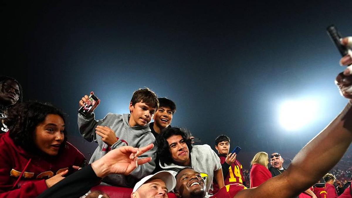  Nov 29, 2025; Los Angeles, California, USA; Southern California Trojans head coach Lincoln Riley (right) and defensive tackle Jahkeem Stewart (4) pose with fans after the game against the UCLA Bruins at United Airlines Field at Los Angeles Memorial Coliseum. Mandatory Credit: Kirby Lee-Imagn Images | Kirby Lee-Imagn Images 