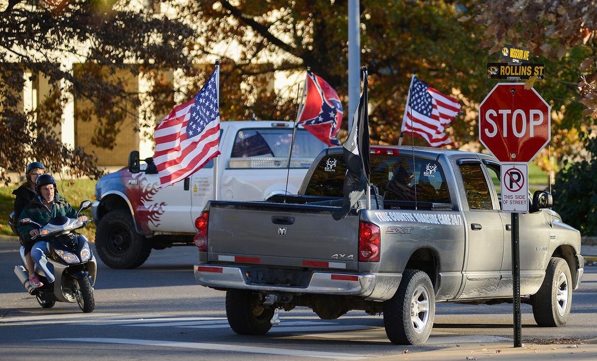 Two trucks bearing the label "True Country Roadside Care" fly a Confederate flag, two United States flags and a POW/MIA flag as they speed by the Concerned Student 1950 campsite on the evening of Nov. 8, 2015, on the Mel Carnahan Quadrangle. The trucks drove by once without stopping. The drivers, 21 and 22-years-old, who asked not to be identified, said they were unaware of the protests happening on campus and were out enjoying the weather.