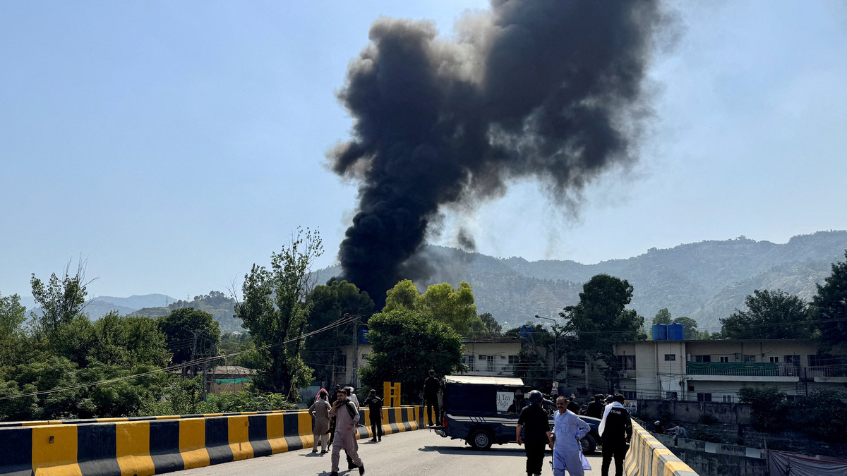 People and police gather nearby as smoke billows from the site where an Mi-17 helicopter of Pakistan Army Aviation crashed near Muzaffarabad, Pakistani Kashmir, June 10, 2026. Picture taken with a mobile phone. REUTERS/Tariq Maqbool