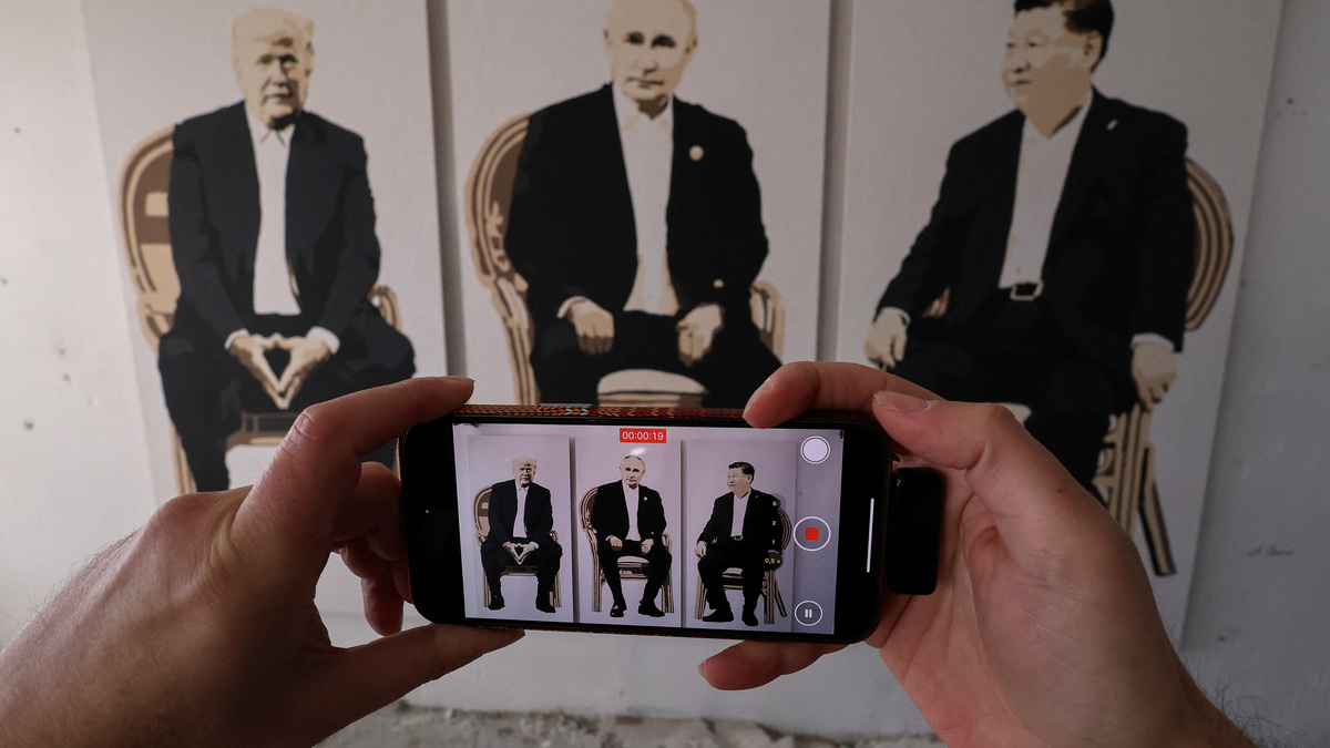 A visitor takes a video of an artwork depicting U.S. President Donald Trump, Russian President Vladimir Putin and Chinese President Xi Jinping at an exhibition, which is called "Yalta 2.0" and opened to make a reference to the 1945 Yalta Conference, at an art gallery in Livadia park in Yalta, Crimea, February 8, 2025. REUTERS/Alexey Pavlishak