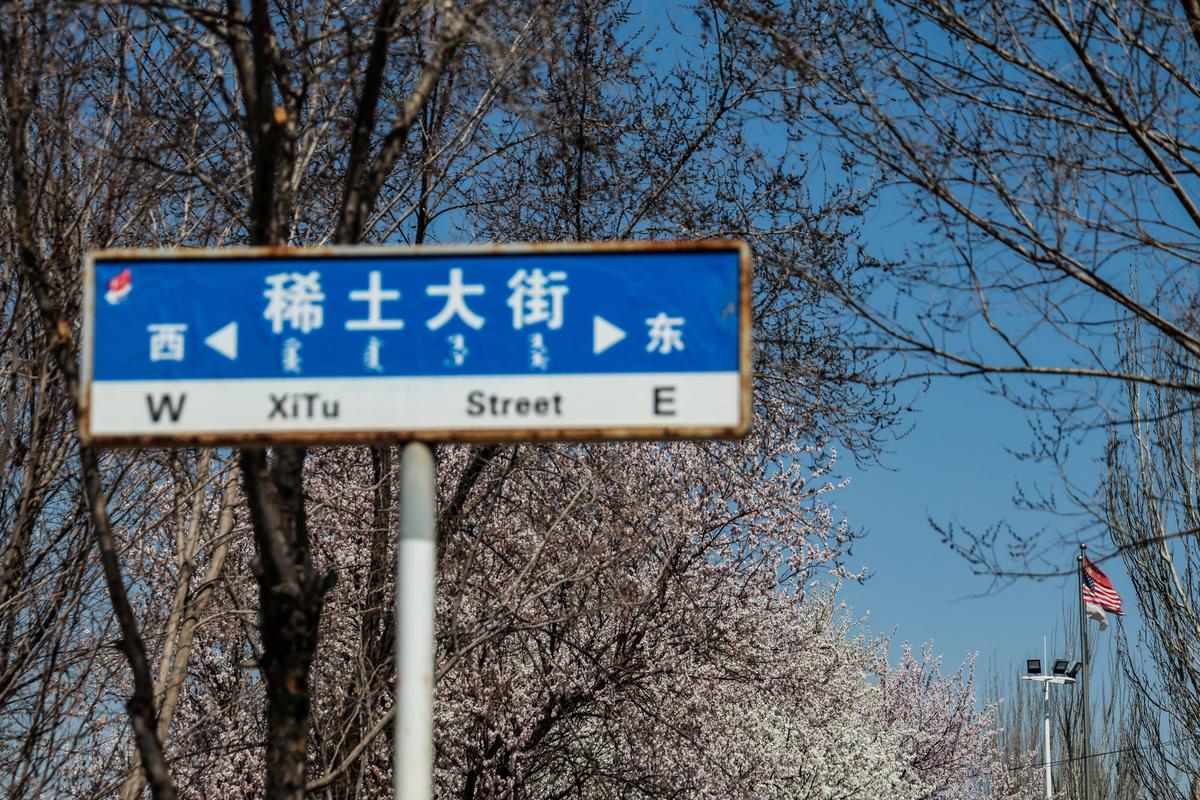 A street sign stands along Xitu (Rare Earth) Street, with China’s and U.S. national flags seen in the background, in China’s rare earth industry hub city Baotou, Inner Mongolia, China, April 6, 2026. REUTERS/Maxim Shemetov