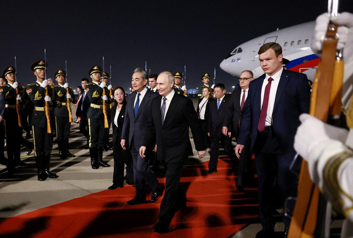 Russian President Vladimir Putin and Chinese Foreign Minister Wang Yi walk past guards of honour during a welcoming ceremony at an airport in Beijing, China, May 19, 2026. Sputnik/Vladimir Smirnov/Pool via REUTERS
