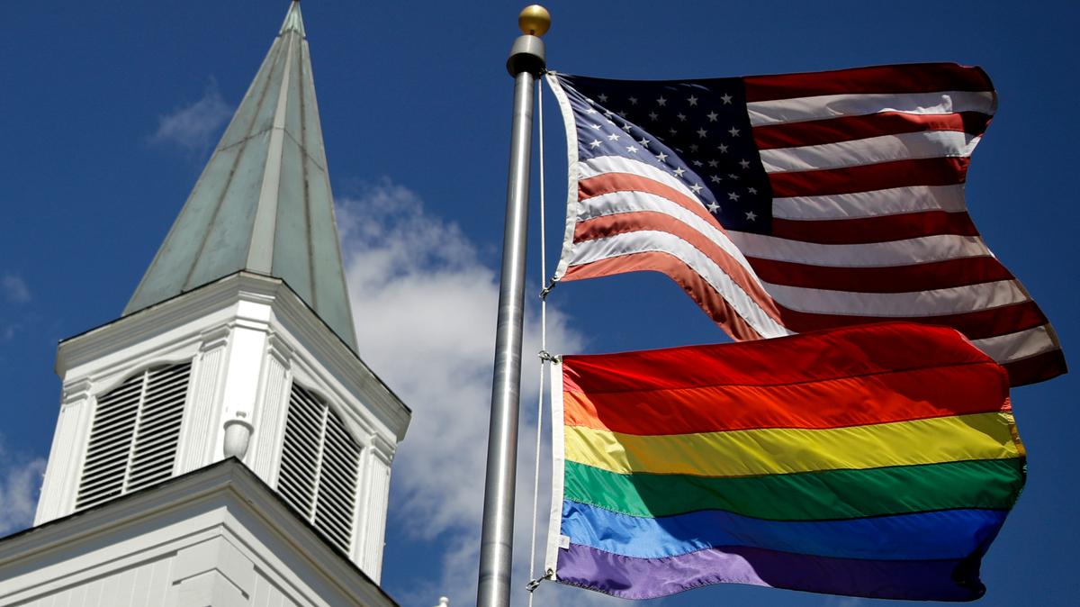 FILE - In this April 19, 2019 file photo, a gay pride rainbow flag flies along with the U.S. flag in front of the Asbury United Methodist Church in Prairie Village, Kan. (AP Photo/Charlie Riedel, File)