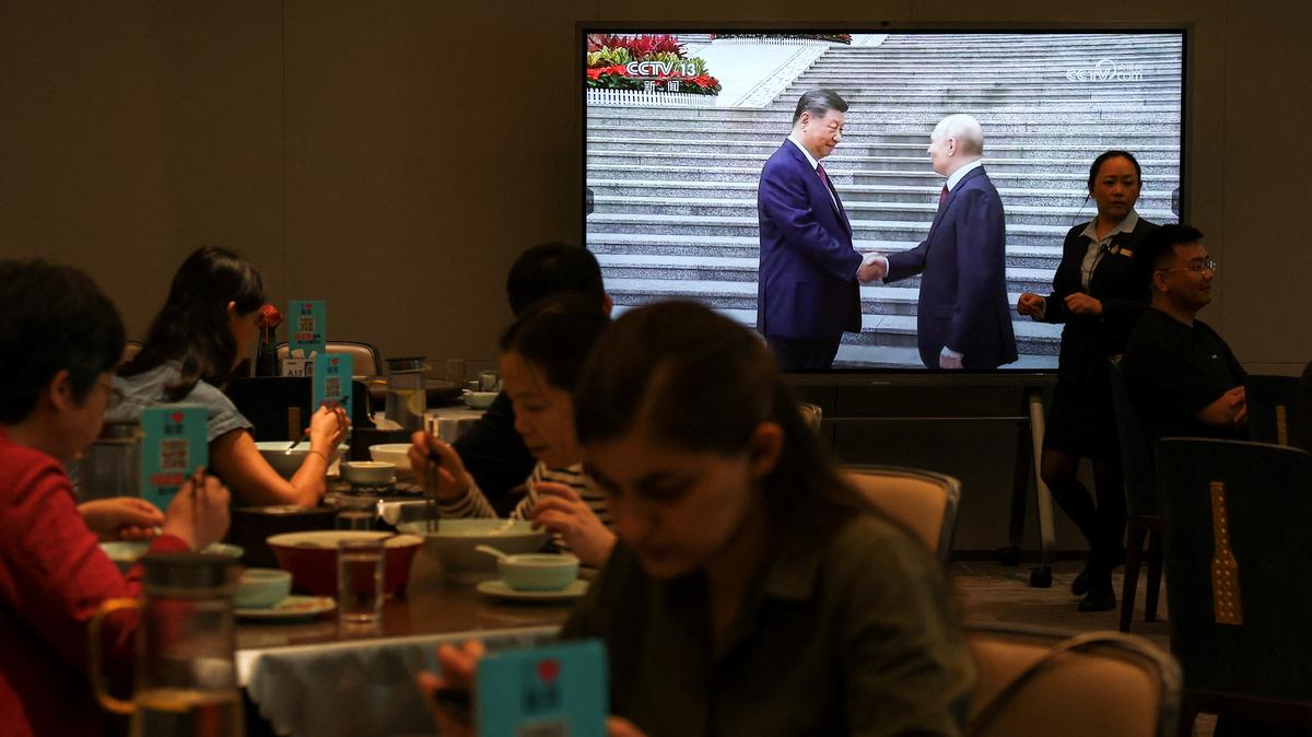 Customers dine near a screen showing a news footage of Chinese President Xi Jinping meeting Russian President Vladimir Putin at the Great Hall of the People, at a restaurant in Beijing, China May 20, 2026. REUTERS/Tingshu Wang