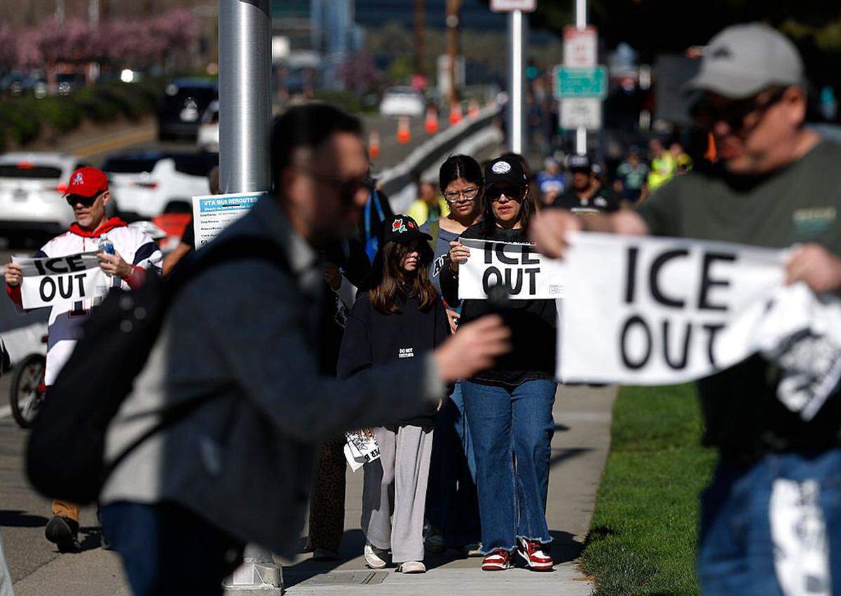 People pass out "ICE out" towels to football fans outside Levi's Stadium before the start of Super Bowl LX on Sunday in Santa Clara, California.