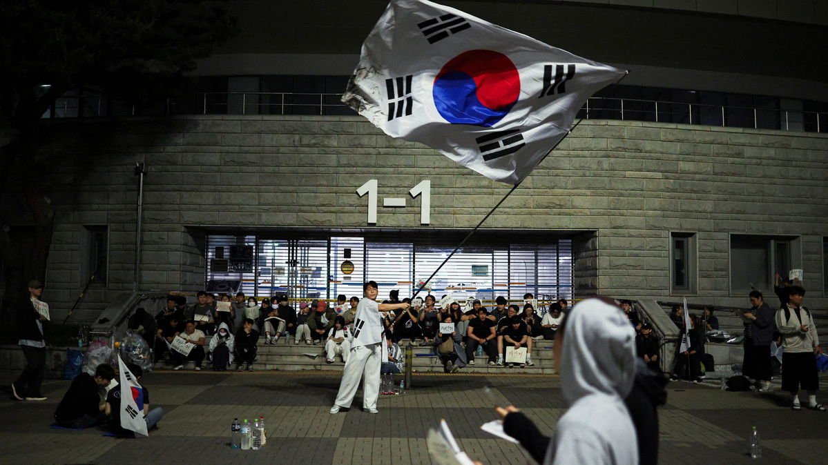 A demonstrator waves a large South Korean flag as people surround a vote-counting centre to protest a controversy over a shortage of ballot papers that disrupted voting in the local election and to call for a rerun of the election, in Seoul, South Korea, June 6, 2026. REUTERS/Kim Hong-Ji