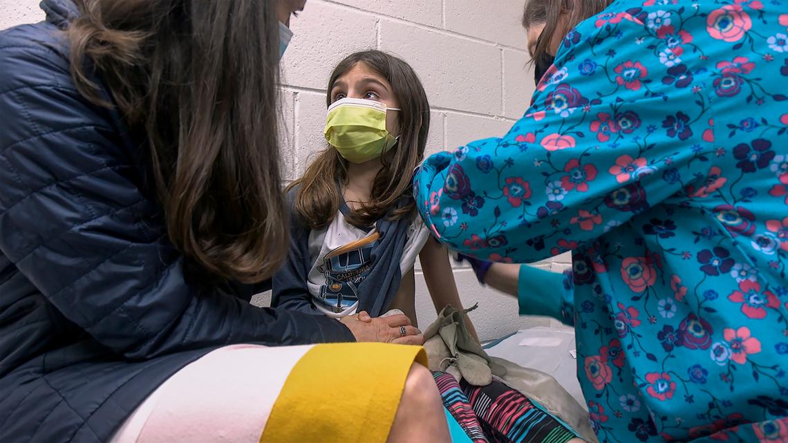 Alejandra Gerardo, 9, looks up to her mom, Dr. Susanna Naggie, as she gets the first of two Pfizer COVID-19 vaccinations during a clinical trial for children at Duke Health in Durham, North Carolina. In the U.S. and abroad, researchers are beginning to test younger and younger kids, to make sure the shots are safe and work for each age.