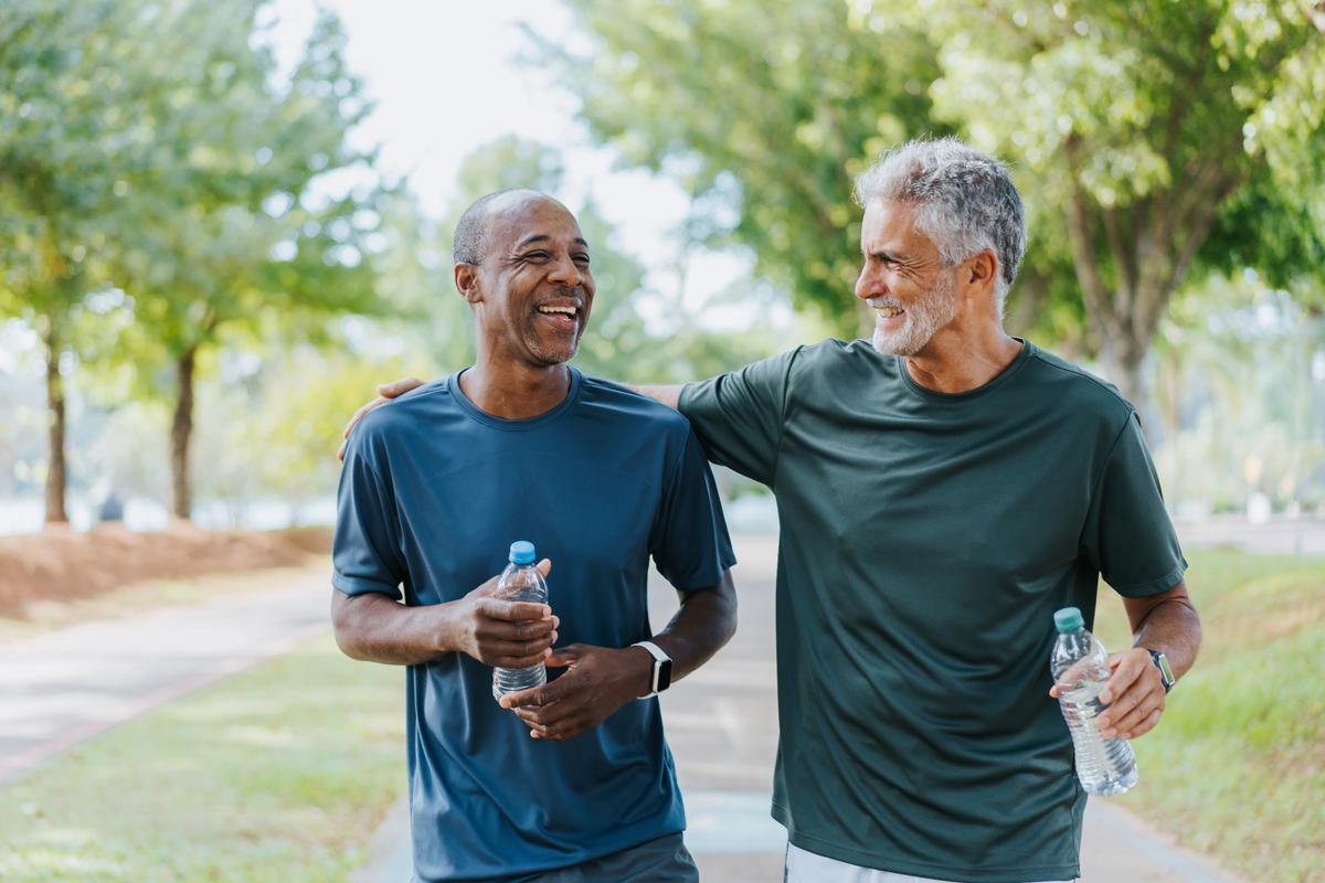 Senior friends walking in public park.