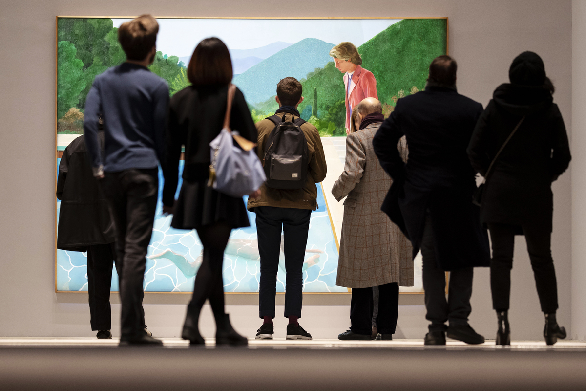 FILE -- People view David Hockney's "Portrait of an Artist (Pool with Two Figures)", the day before it was auctioned for $90 million, at Christie's in New York, Nov. 14, 2018. Hockney, whose colorful figurative paintings were both conservative and iconoclastic, defying the dominant abstract schools of the mid-20th century, died at home in London on June 11, 2026. He was 88. (Karsten Moran/The New York Times)