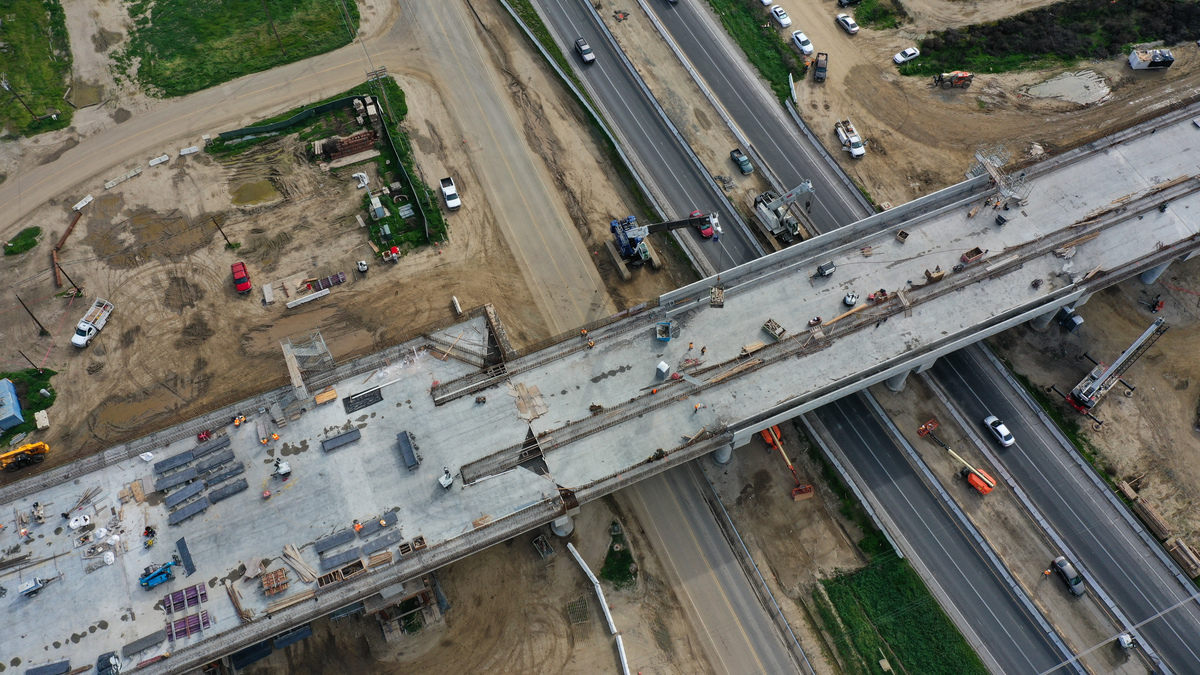 An aerial image shows construction workers building the Hanford Viaduct over Highway 198 and past agricultural fields as part of the California High Speed Rail (CAHSR) transit project in Hanford, California, on February 12, 2025. The Hanford Viaduct is the largest high-speed rail structure in the Central Valley over 6,000 feet long. (Photo by Patrick T. Fallon / AFP) (Photo by PATRICK T. FALLON/AFP via Getty Images).