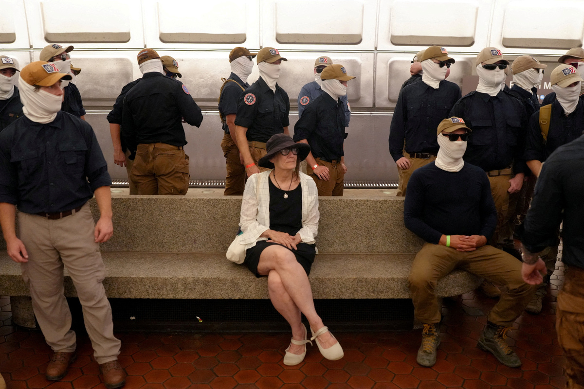 A commuter sits as members of the group Patriot Front stand at the Eastern Market metro station, on the 250th anniversary of U.S. independence in Washington, D.C., U.S., July 4, 2026. REUTERS/Nathan Howard
