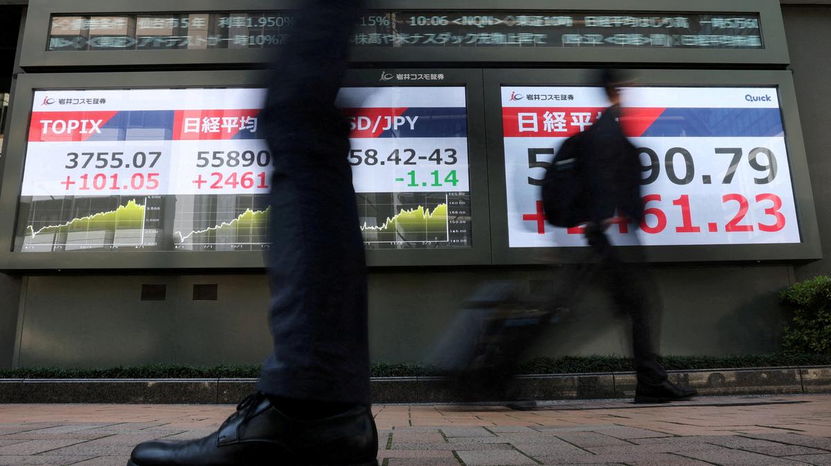 FILE PHOTO: Passersby walk past screens displaying Japan's Nikkei share average, exchange rate between Japanese yen and U.S. dollar and the Tokyo Stock Price Index (TOPIX) outside a brokerage in Tokyo, Japan April 8, 2026. REUTERS/Issei Kato/File Photo