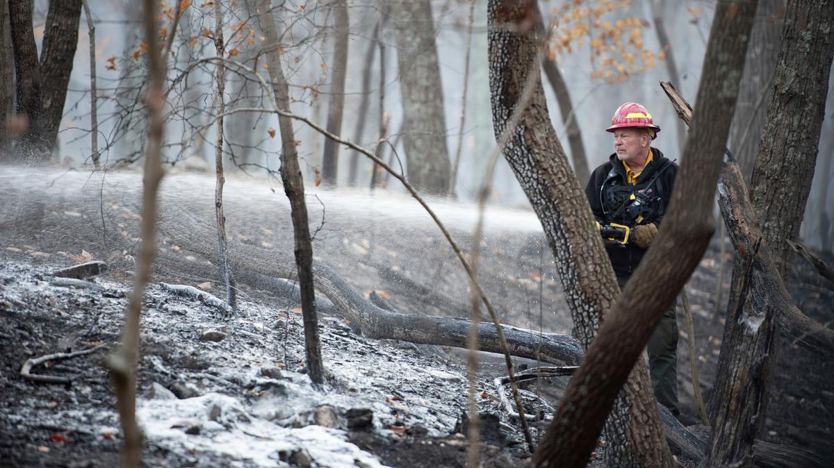 A firefighter with the North Carolina Forest Service sprays remaining hot spots from the wildfire at Pilot Mountain State Park that caused damage to over 1,000 acres in Pinnacle, N.C.