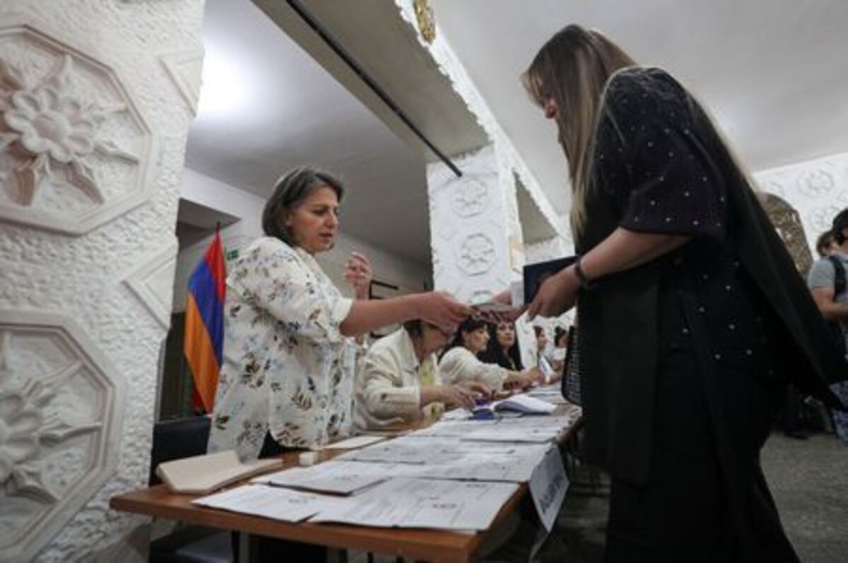 A voter receives a ballot from an official at a polling station during a parliamentary election in Yerevan, Armenia, June 7, 2026. Hayk Baghdasaryan/Photolure via REUTERS