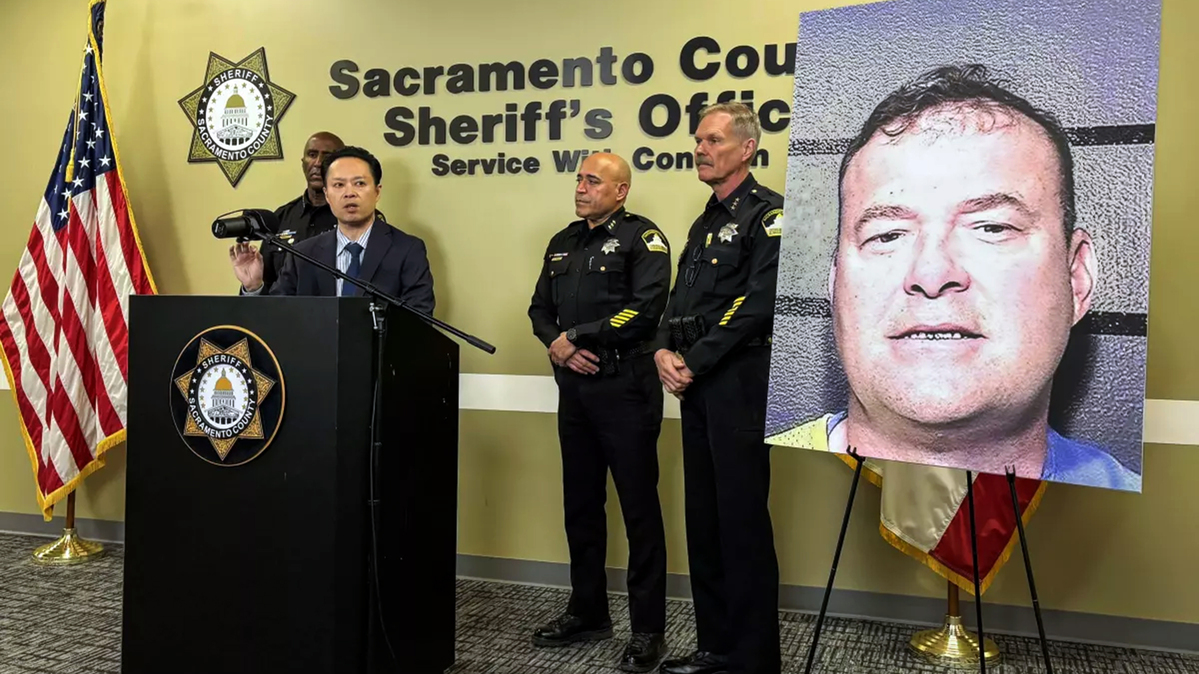 Sacramento County Dist. Atty. Thien Ho, center, speaks during a news conference on Thursday. Ho called for reform to California's Elderly Parole Program in response to the planned release of Gregory Vogelsang, pictured on the poster. (Kate Wolffe/Sacramento Bee/TNS)
