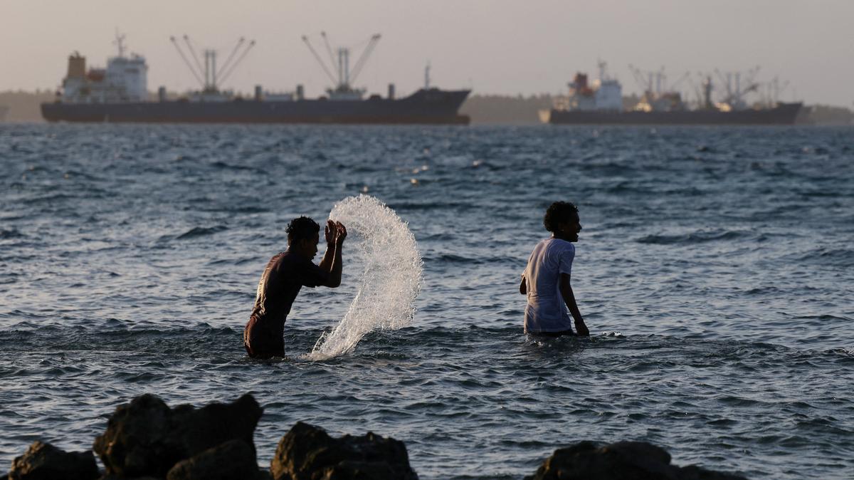 Kids play in the water, as fishing boats pass by, in Majuro lagoon, Marshall Islands, June 17, 2025. REUTERS/Hollie Adams