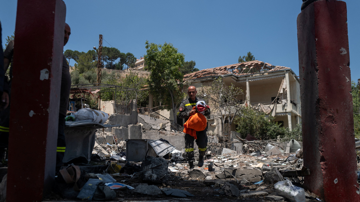 A member of the government-run Lebanese Civil Defense, the country's primary firefighting, first aid, and rescue force, holds a national flag and personal belongings salvaged from the rubble while inspecting their headquarters in Nabatieh, Lebanon, June 17, 2026, following the deal between the United States and Iran. The headquarters was destroyed in an Israeli airstrike in May. REUTERS/Zohra Bensemra