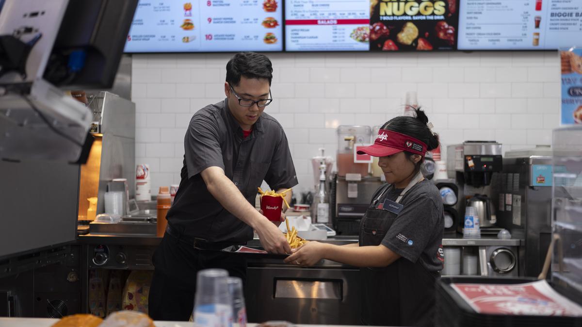 California Fast Food Wages. Lawrence Cheng, left, whose family owns seven Wendy's locations south of Los Angeles, works with part-time employee Adriana Ruiz at his Wendy's restaurant in Fountain Valley, California, on June 20, 2024.