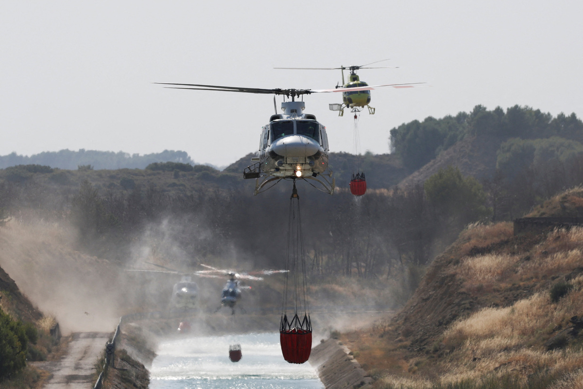 Firefighting helicopters load water to battle wildfires affecting Zaragoza province, in Farasdues, Spain, July 16, 2026. REUTERS/Violeta Santos Moura