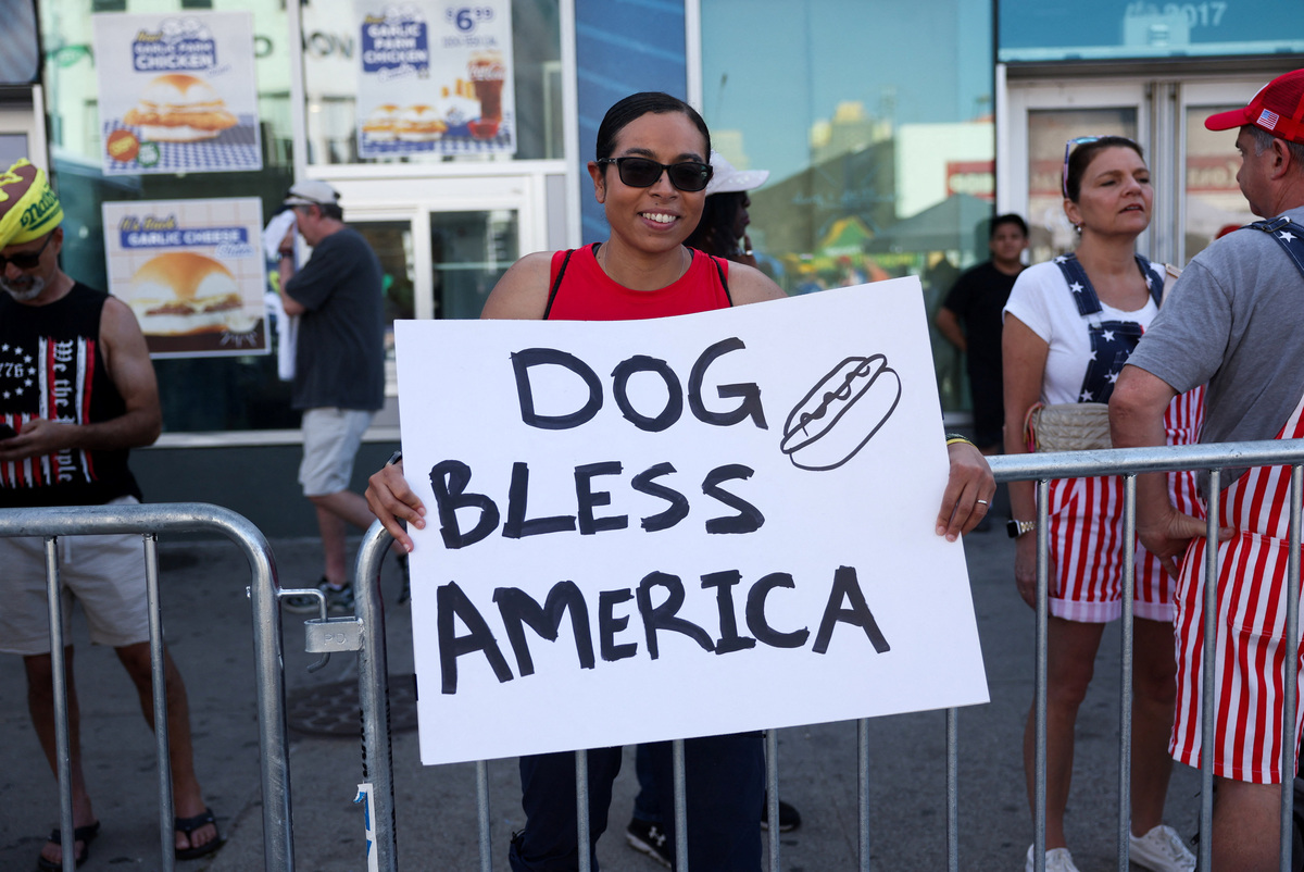 A woman holds a placard on the day of the 2026 Nathan's Famous International Hot Dog Eating Contest, at Coney Island, Brooklyn in New York City, U.S., July 4, 2026. REUTERS/Jordan Tovin