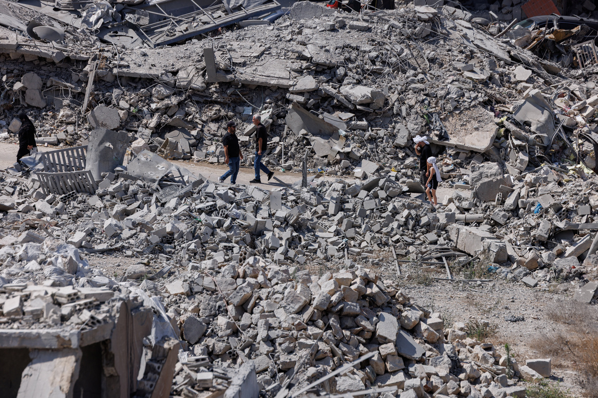 People walk past buildings destroyed by an Israeli airstrike during the interim period following the U.S.-Iran deal, in Nabatieh, southern Lebanon, June 26, 2026. REUTERS/Zohra Bensemra