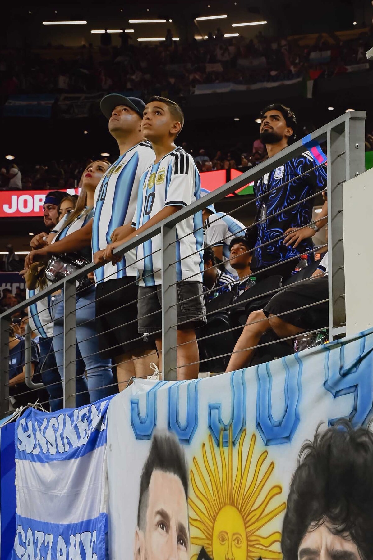 A sign showing Argentina's Lionel Messi and the late Diego Maradona is displayed during the FIFA World Cup Group match between Argentina and Jordan in Dallas, Texas, June 27, 2026. A multimillion-dollar battle for a soccer god's brand is being waged across continents, burning investors and tearing his family apart. (Desiree Rios/The New York Times)